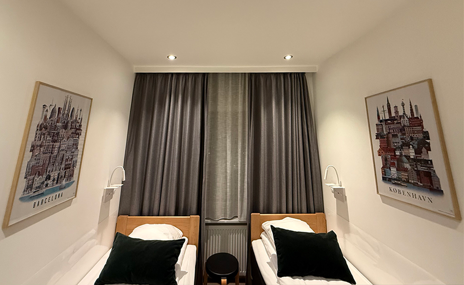 Hotel room with a Barcelona poster on the left wall and a Copenhagen poster on the right wall